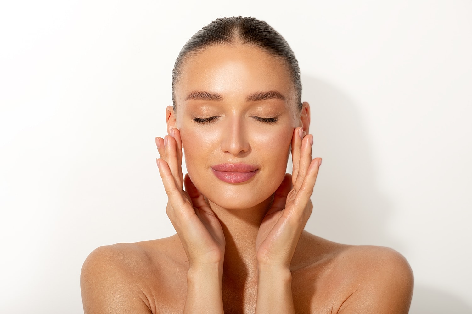 Young woman with glowing skin, eyes closed.