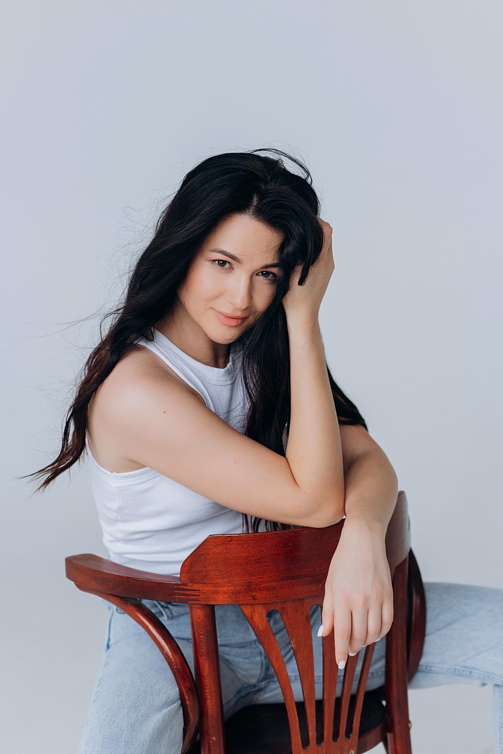 Woman sitting on chair, posing thoughtfully.