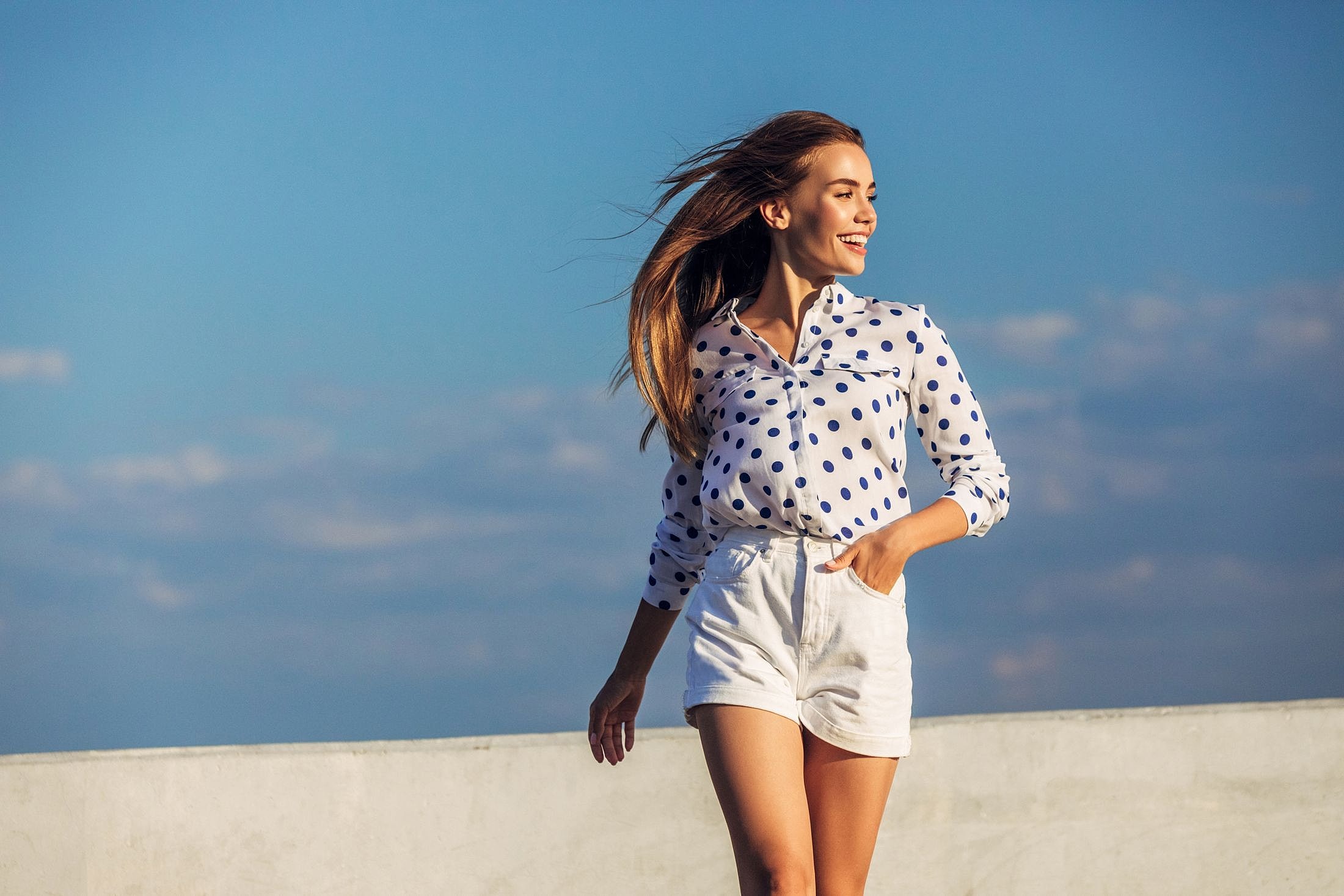 Woman in polka dot shirt against blue sky.